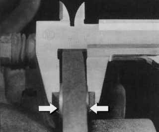 Измерение толщины тормозного диска с использованием двух монет, расположенных с обеих сторон диска между штангенциркулем и тормозным диском